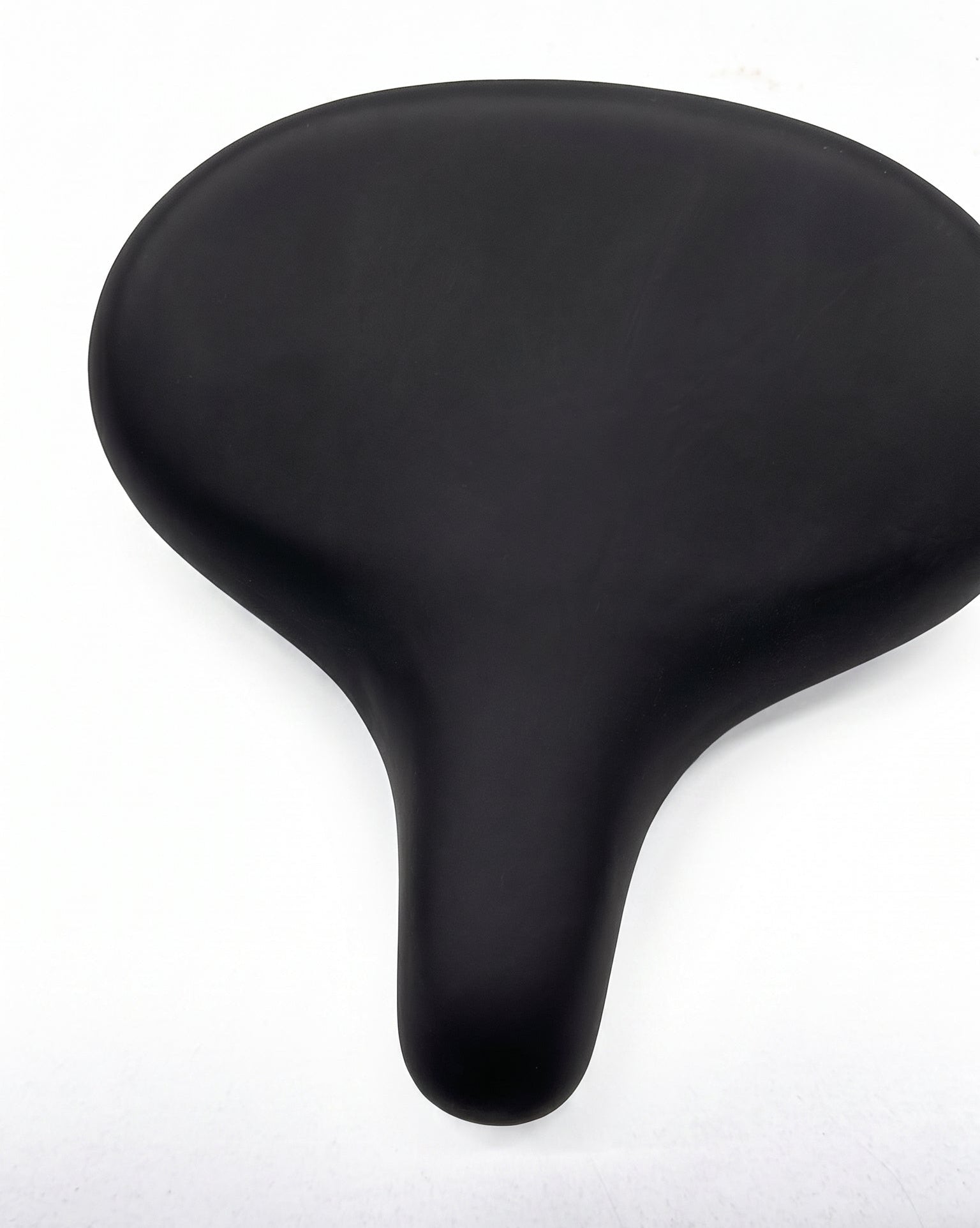 A black bicycle saddle with a smooth, matte finish, photographed from a top-down perspective on a white background.
